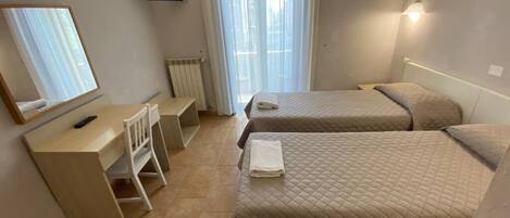 Habitación de hotel con dos camas, un escritorio, una silla, un televisor y una ventana con cortinas.