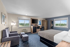 A hotel room with a bed, a desk, a chair, a sofa, and a TV.