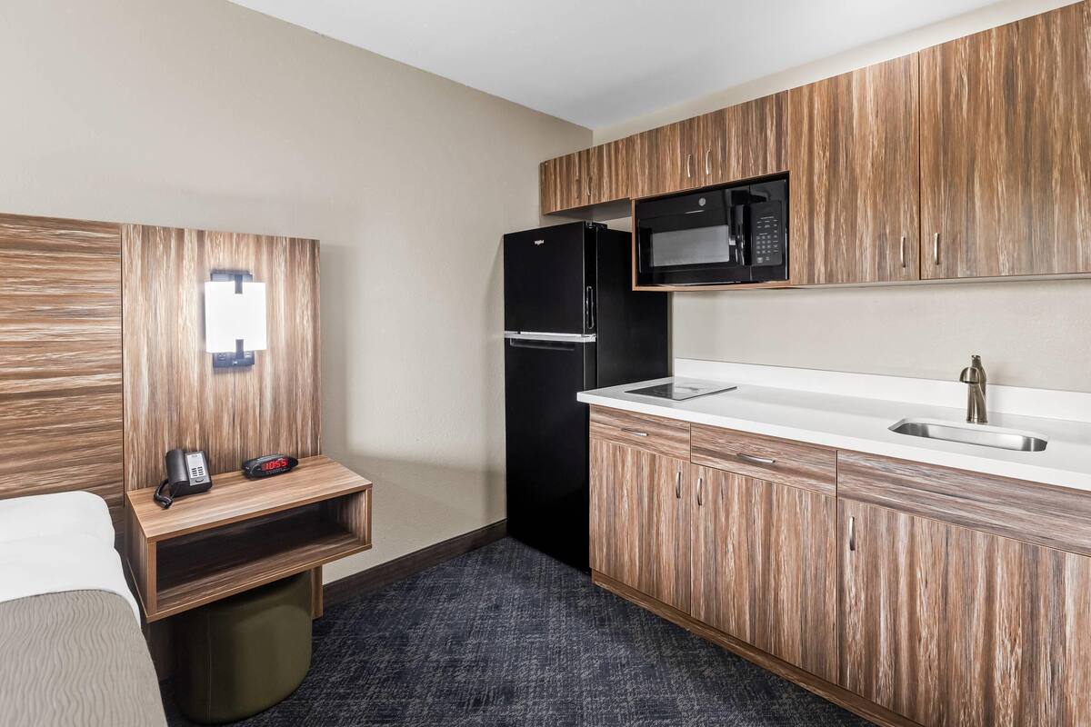 A compact kitchen with a refrigerator, microwave, and sink.