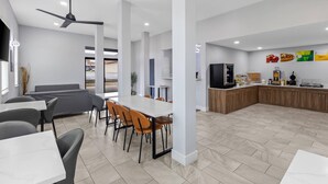 A modern kitchen with a central island, a dining area with tables and chairs, and a seating area with a sofa.