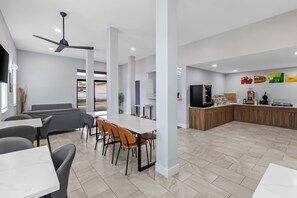 A modern kitchen with a central island, a dining area with tables and chairs, and a seating area with a sofa.