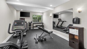 A gym with treadmills, dumbbells, a bench, and a mirror.
