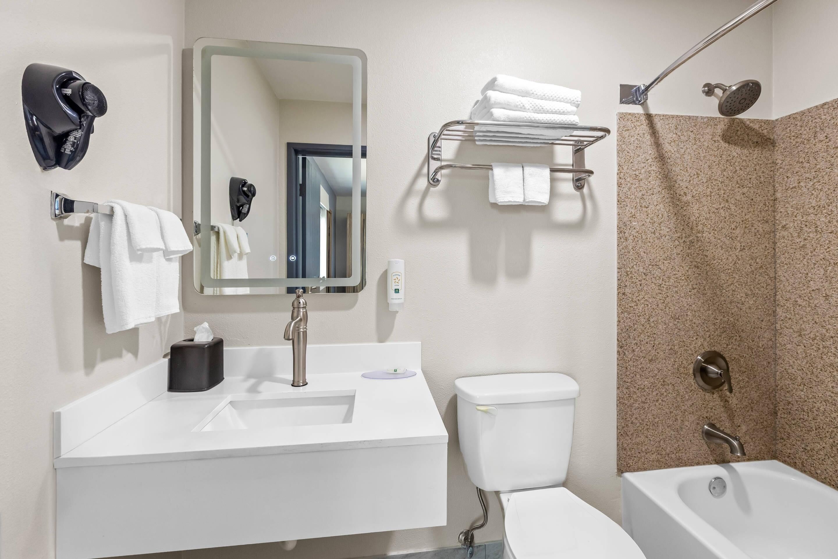 Een moderne badkamer met een wastafel, toilet en bad.