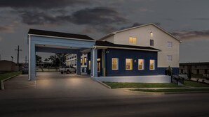 A two-story building with a covered parking area and a well-lit entrance.