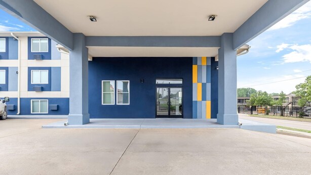A building entrance with a blue facade, a glass door, and a parking area.