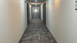 A hotel hallway with a patterned carpet, doors on both sides, and a sign indicating room number 204.