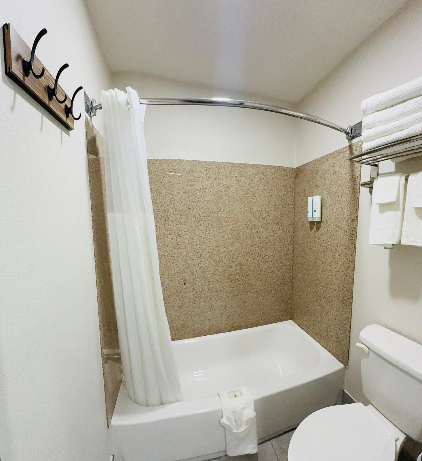 A bathroom with a bathtub, a shower curtain, a towel rack, and a toilet.