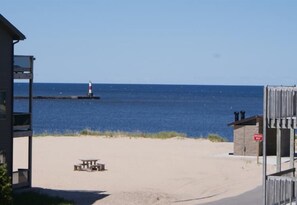 Una playa con una mesa de picnic, un faro a lo lejos y un cartel que indica 'No natación'.