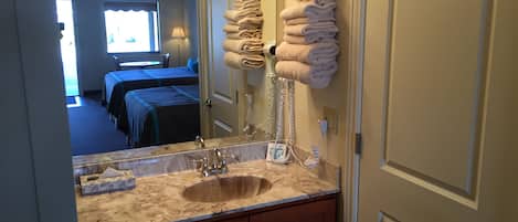 Un baño con lavabo, espejo, toallero y puerta.