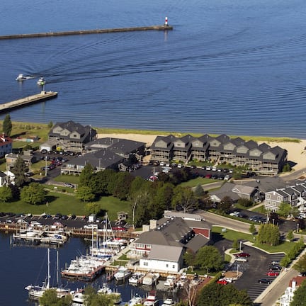 A marina with boats, a lighthouse, and a residential area with houses and a parking lot.