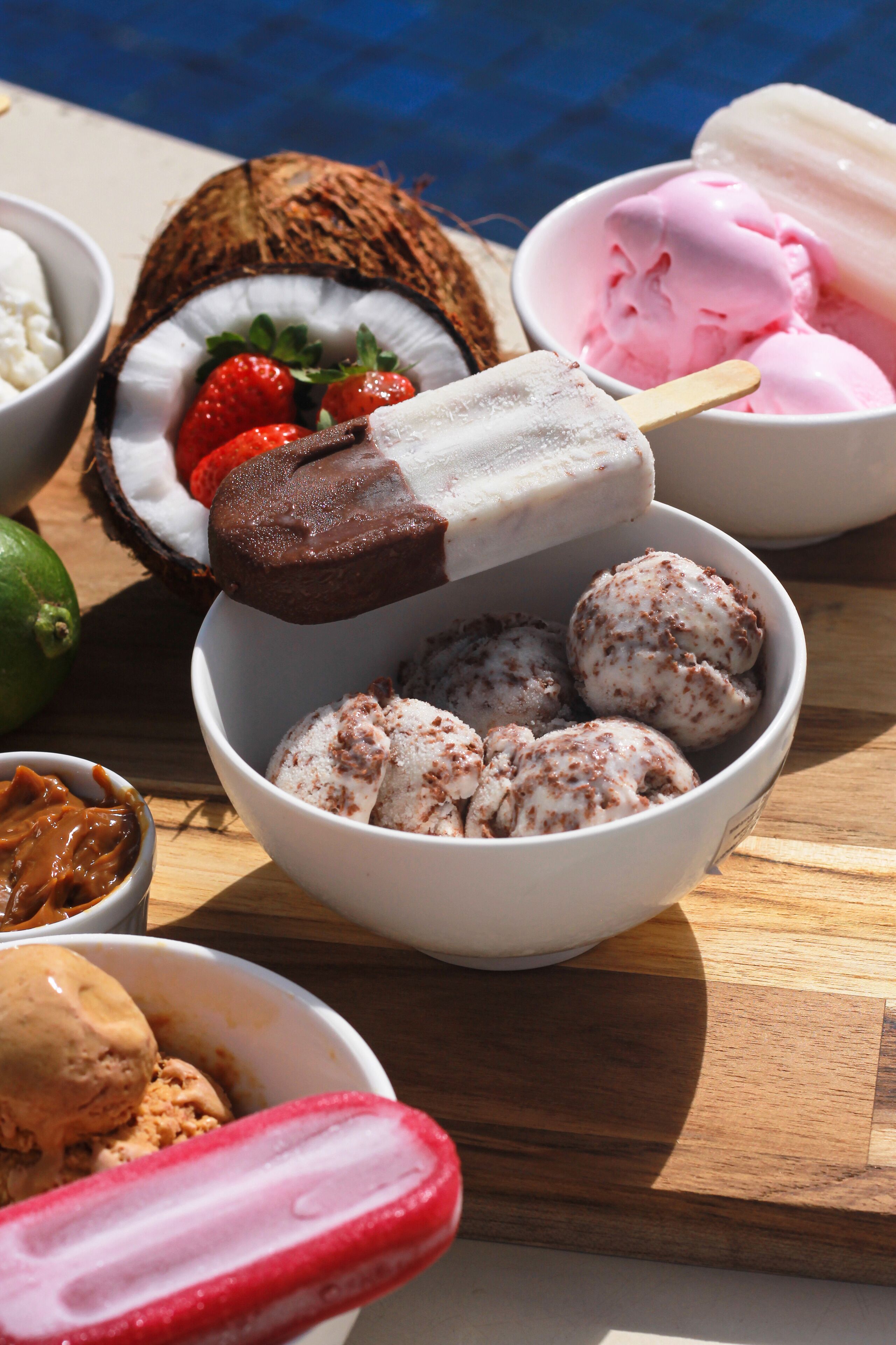 A bowl of ice cream with a chocolate bar on top, surrounded by various other ice cream flavors.
