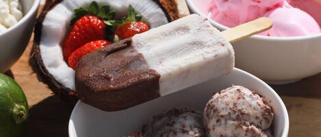 A bowl of ice cream with a chocolate bar on top, surrounded by various other ice cream flavors.