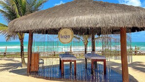 Un spa frente a la playa con techo de paja, un cartel que dice "leger SPA" y vistas al océano.