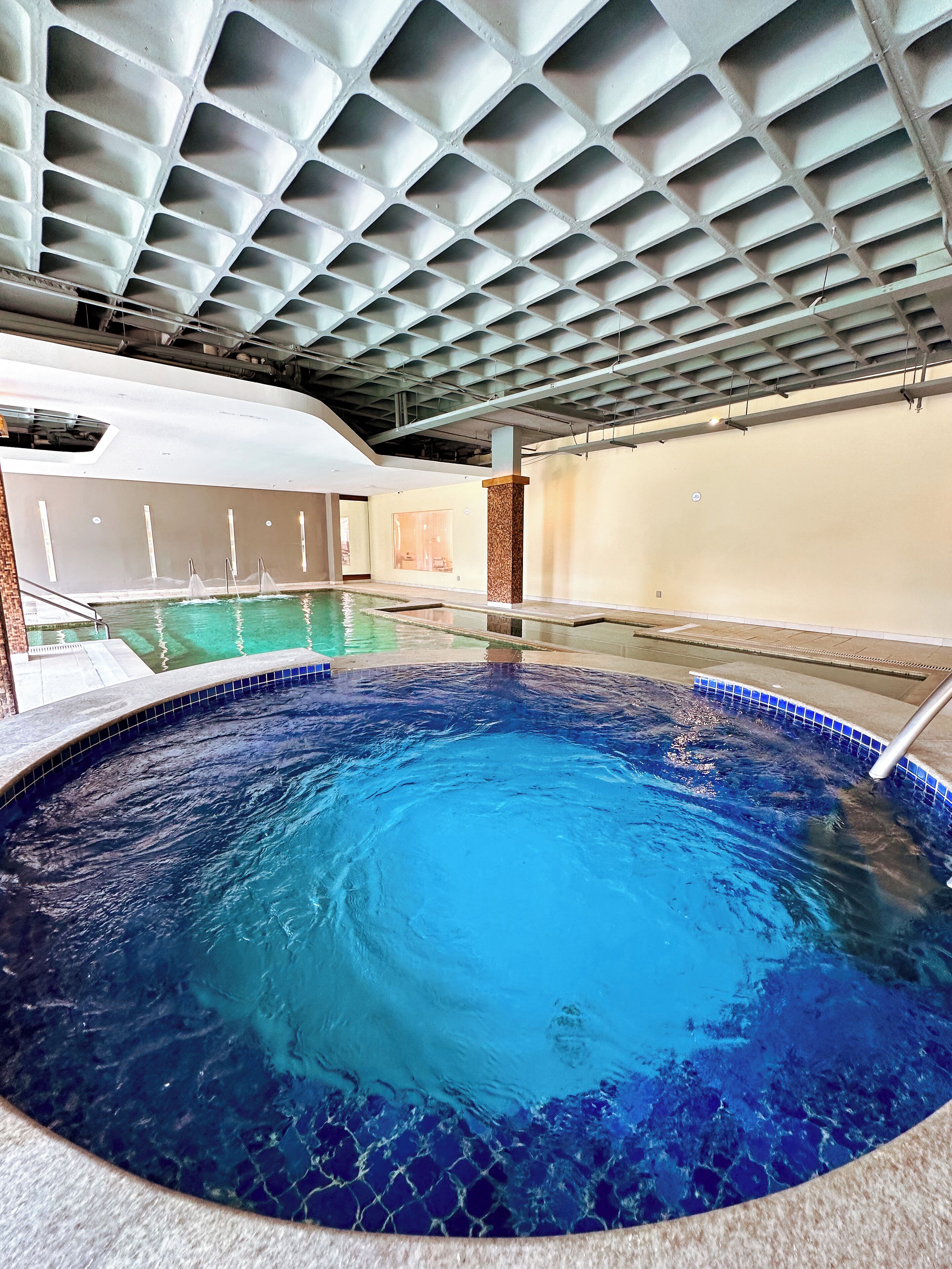 Ein überdachter Pool mit klarem, blauem Wasser, einer Decke mit Rasteroptik und einem gefliesten Boden.