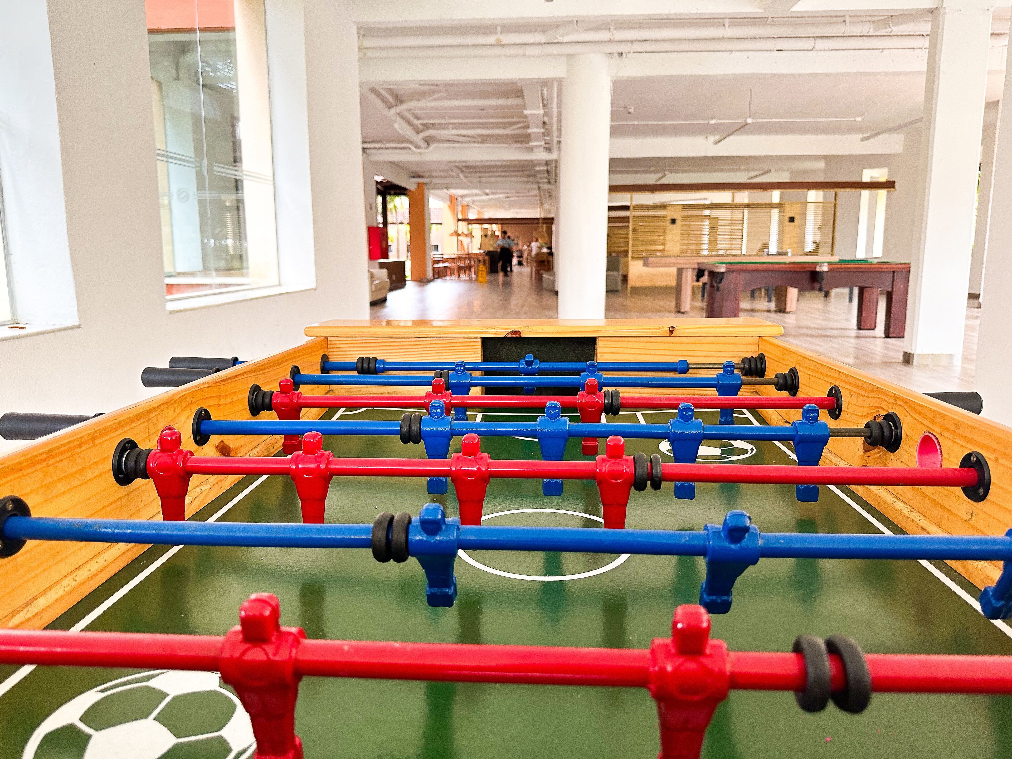 A foosball table in a brightly lit indoor space with white walls and large windows.