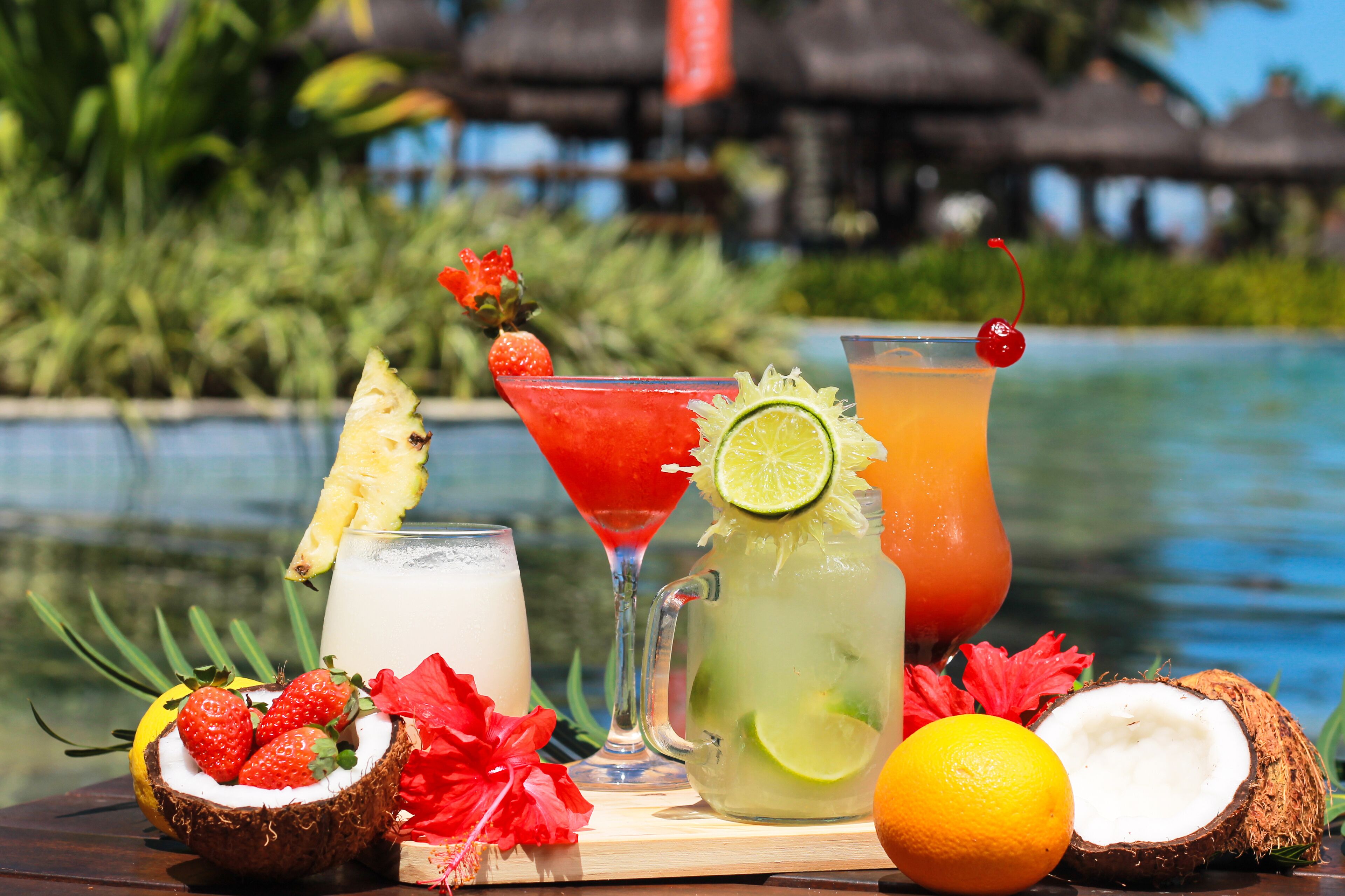 A tropical drink setup with a pool in the background.