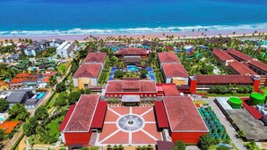Vista aérea de un resort con varias construcciones, un patio central de diseño en forma de estrella y una playa al fondo.