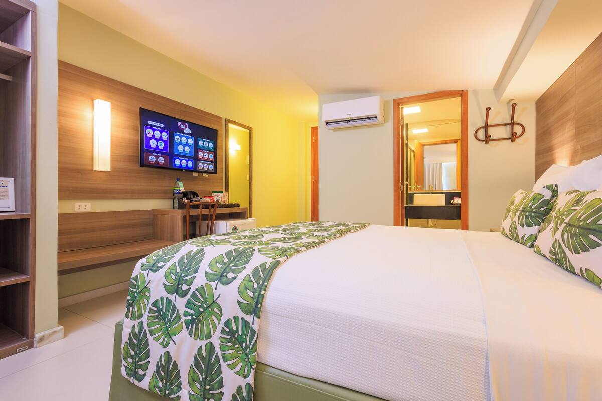 Habitació d'hotel amb llit, escriptori, televisió i aire condicionat.