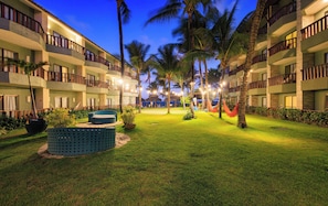 Un patio de hotel con piscina, palmeras y zona de estar.