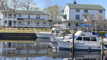 Un port de plaisance avec des bateaux amarrés, une maison blanche avec un toit vert et un ciel dégagé.