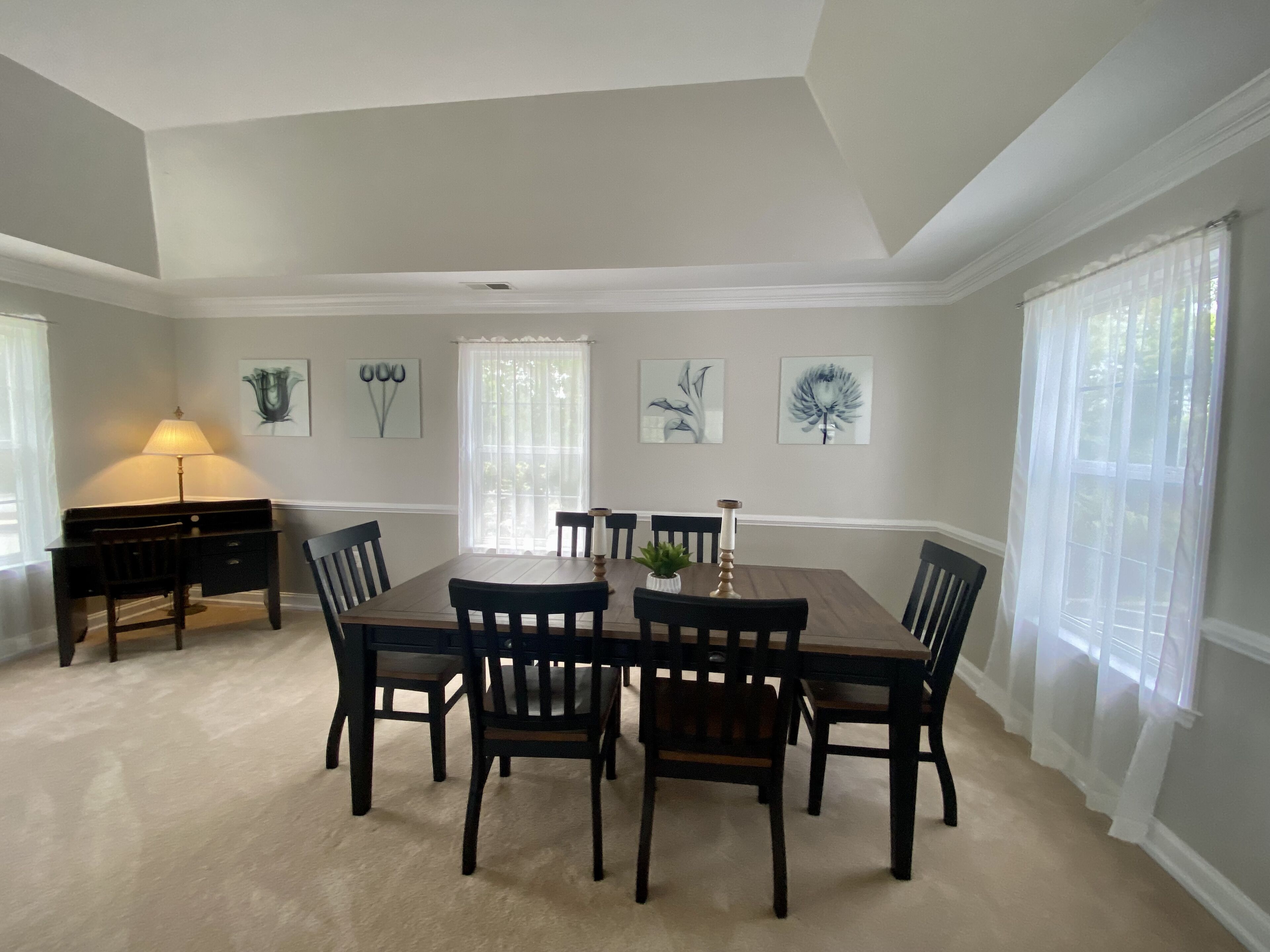 A dining room with a large table and chairs, a lamp, and artwork on the walls.
