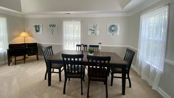 A dining room with a large table and chairs, a lamp, and artwork on the walls.