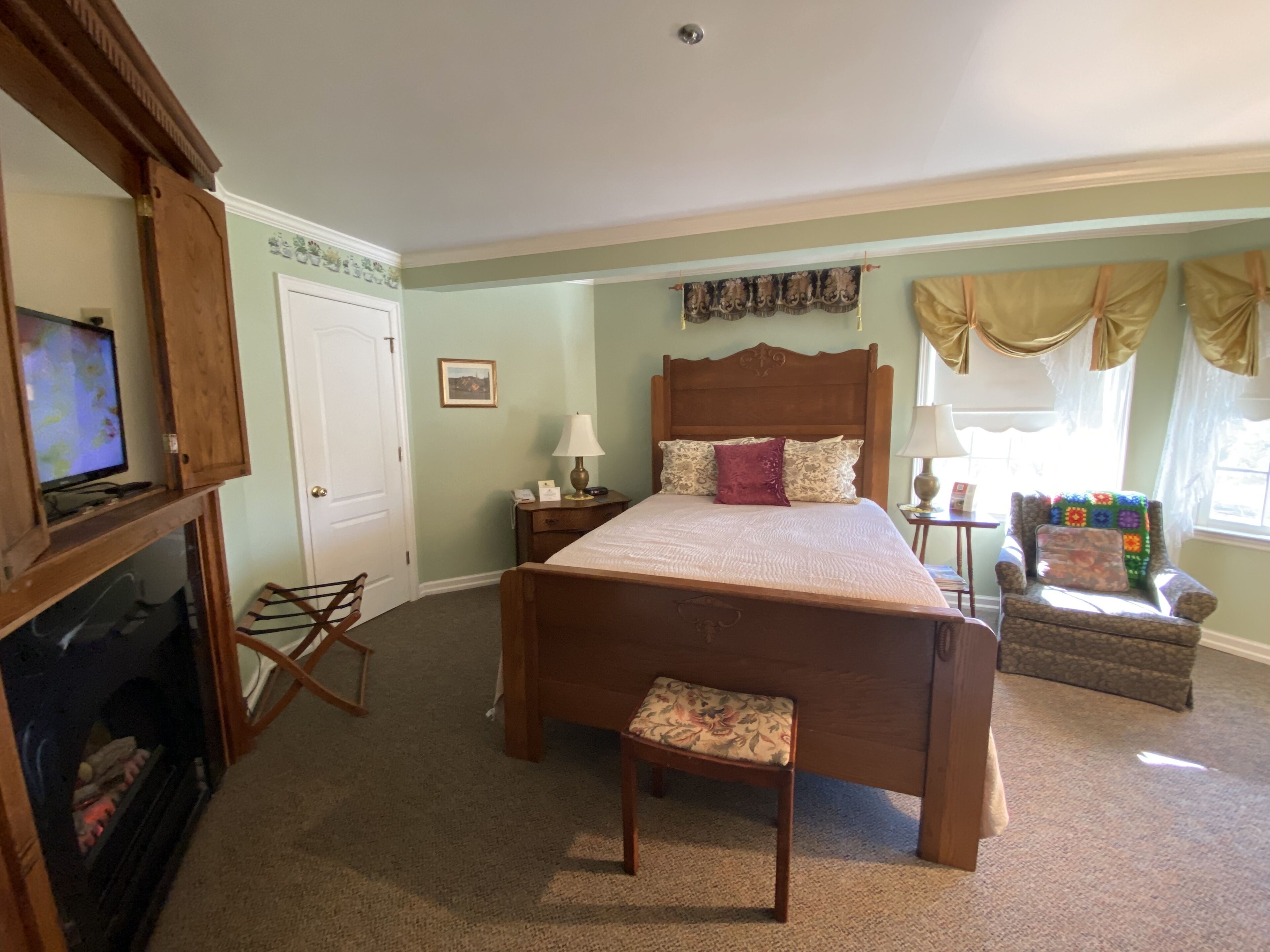 Un dormitorio con una cama de madera, un televisor, una silla y una mesita.