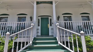 Un edificio blanco con una puerta verde y un letrero que dice "The Cypress Inn".