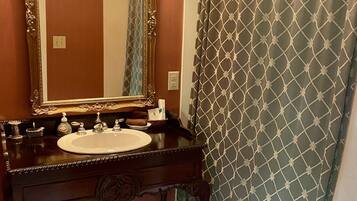 A bathroom with a vanity, sink, mirror, and shower curtain.