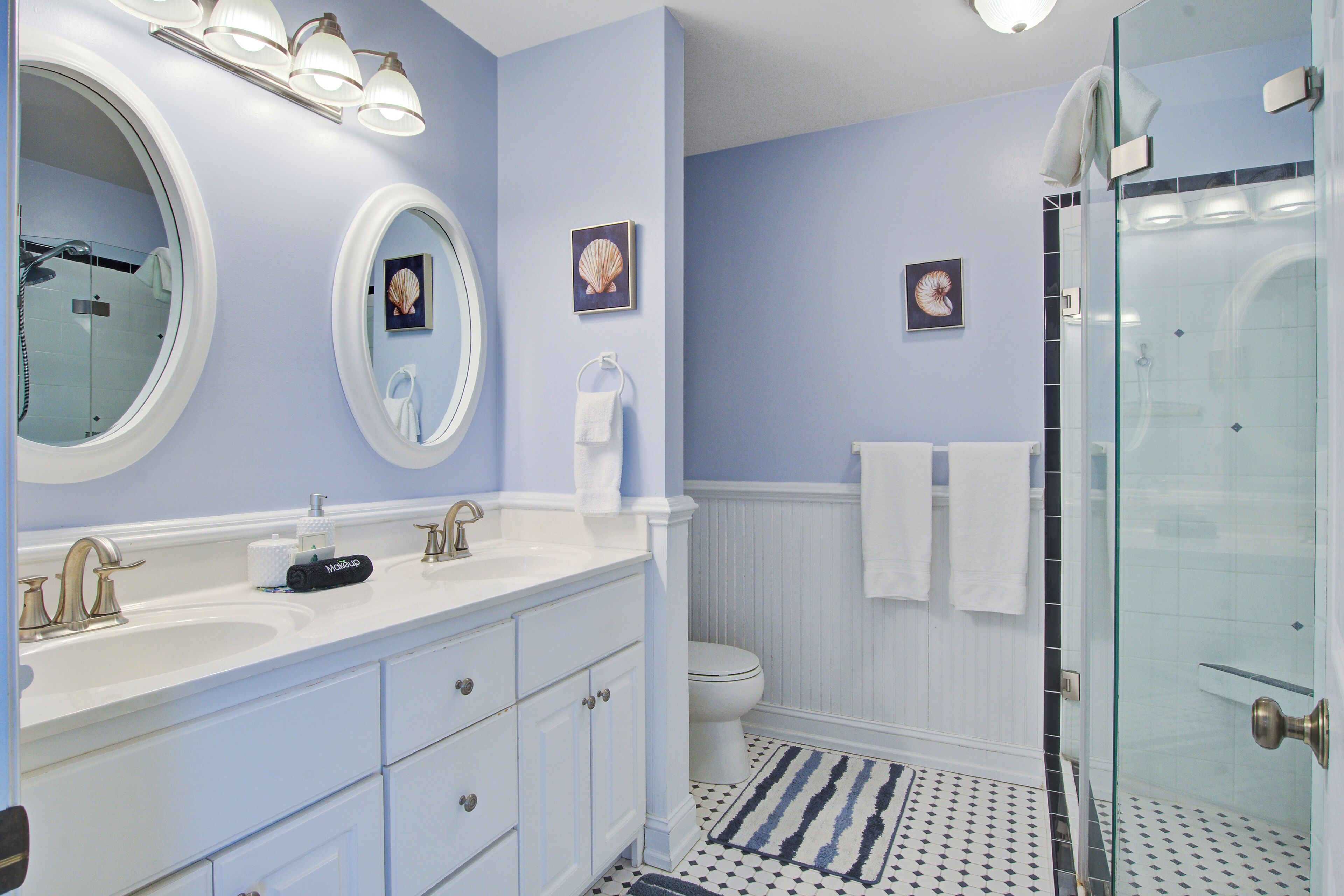 A bathroom with a large mirror, a sink, a toilet, and a shower.