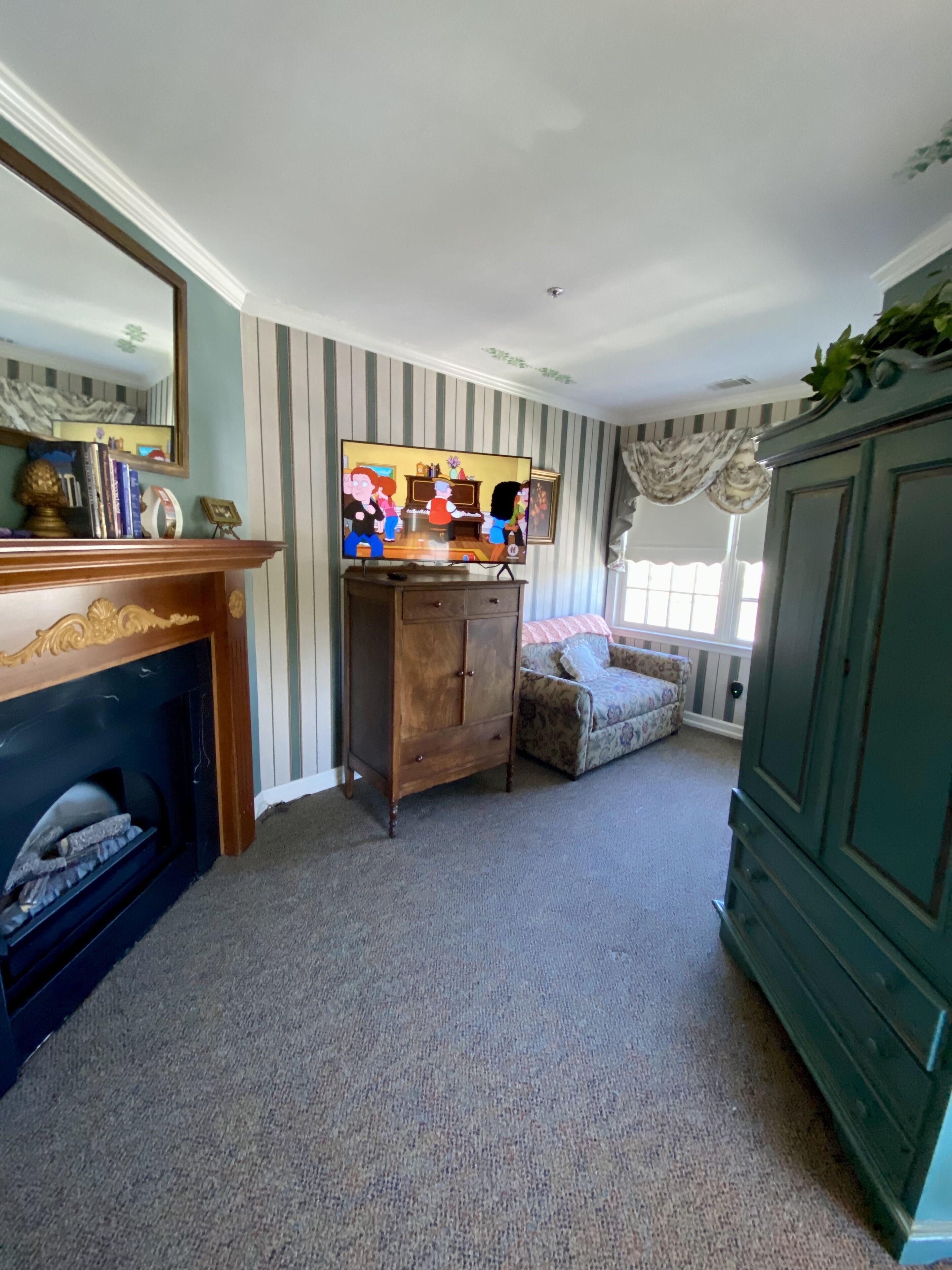 A room with a fireplace, a television, a sofa, and a cabinet.