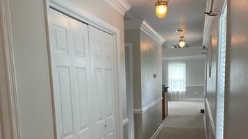 A hallway with white doors, beige carpet, and wall-mounted lighting fixtures.