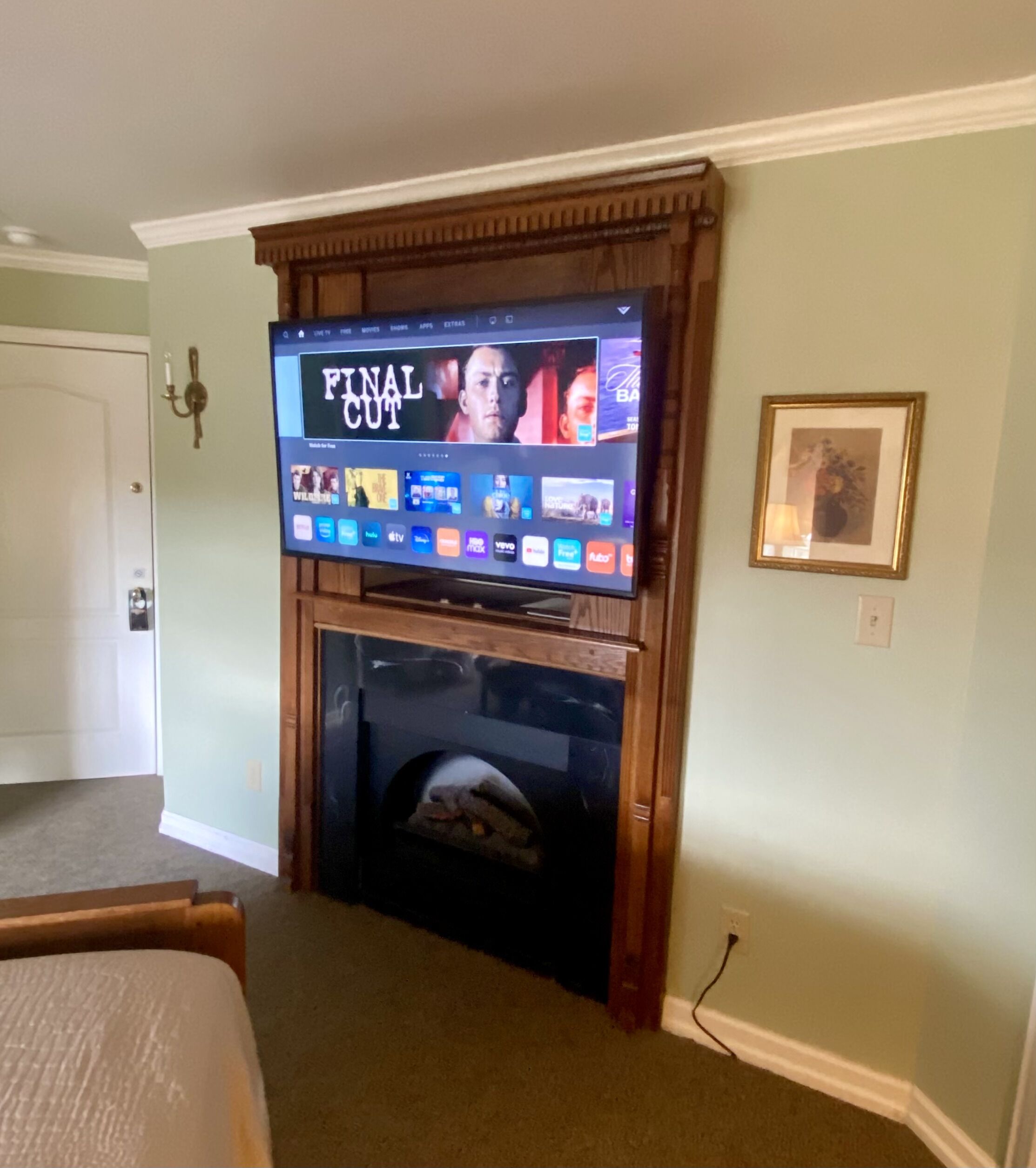 A television mounted on a wooden wall above a fireplace, displaying the 'Final Cut' menu.