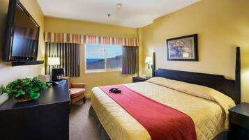 Een hotelkamer met een bed, een bureau met lamp, een televisie en een raam met gordijnen.