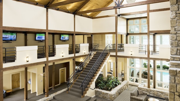 A spacious indoor area with a stone wall, a staircase, and multiple seating areas. - Steele Hill Resorts (Sanbornton)