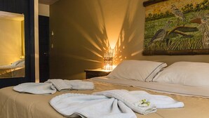 A hotel room with a bed, towels, a painting, and a nightstand with a lamp. - Pousada Aguape (Aquidauana)