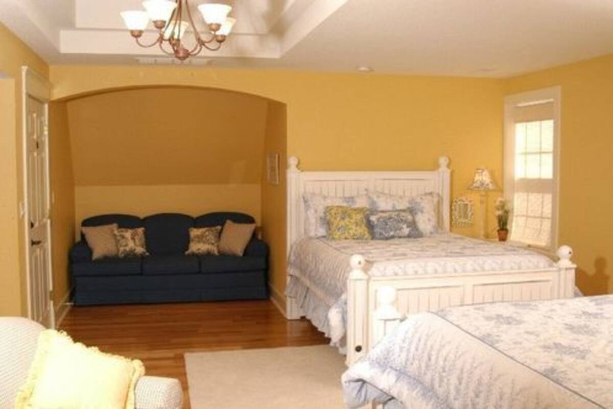 A bedroom with a bed, a sofa, and a chandelier.