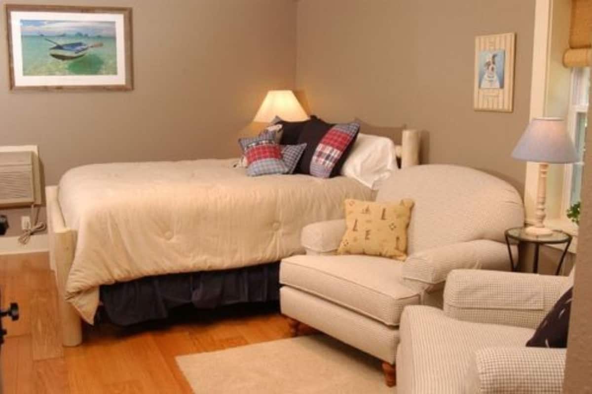 A bedroom with a bed, bedside table, lamp, and a small sofa.