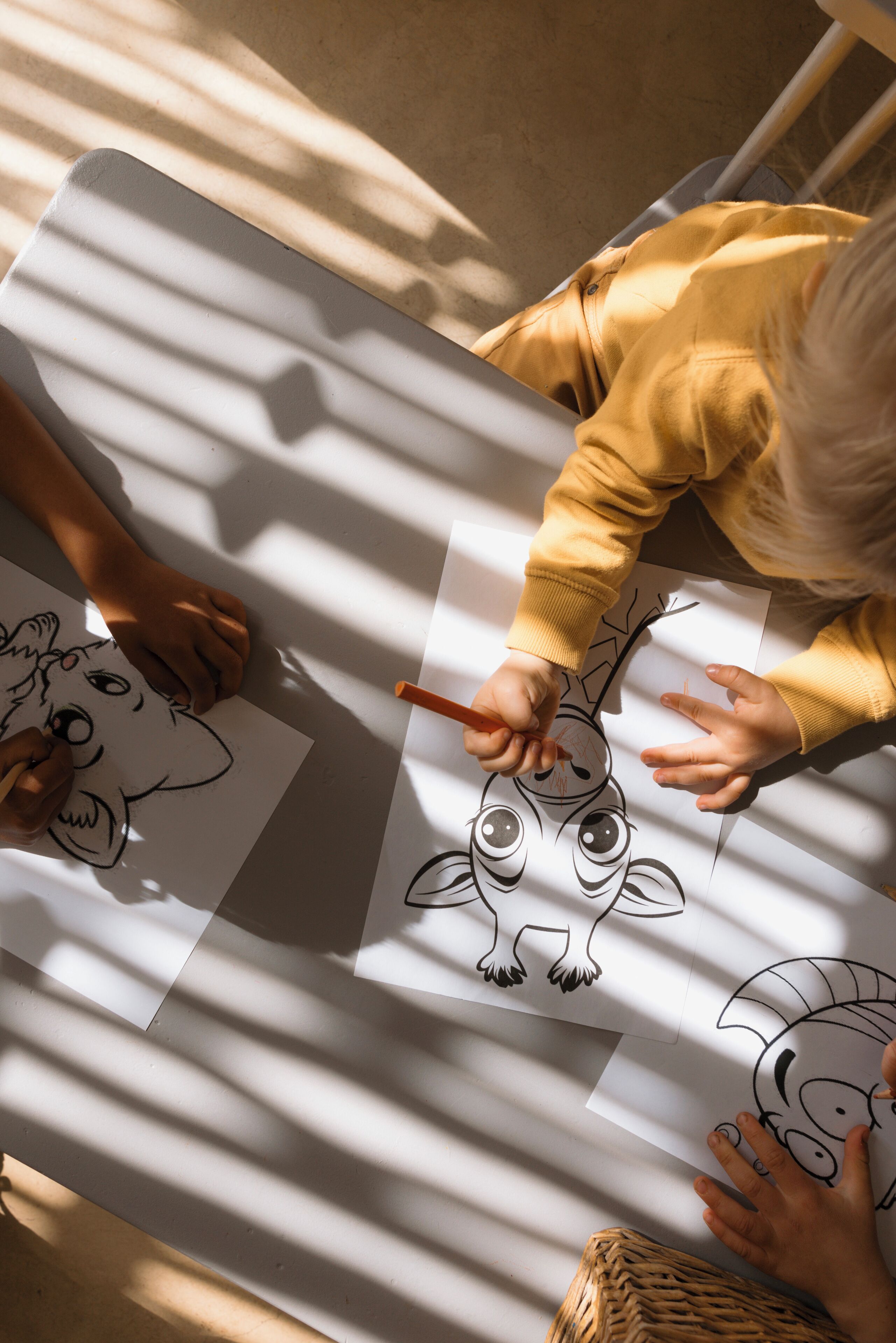 A child drawing on a paper with a pencil, with another child observing.