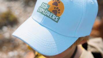 Gros plan d’une casquette bleu clair ornée d’une empreinte de patte et du texte « ECO EXPLORERS ».