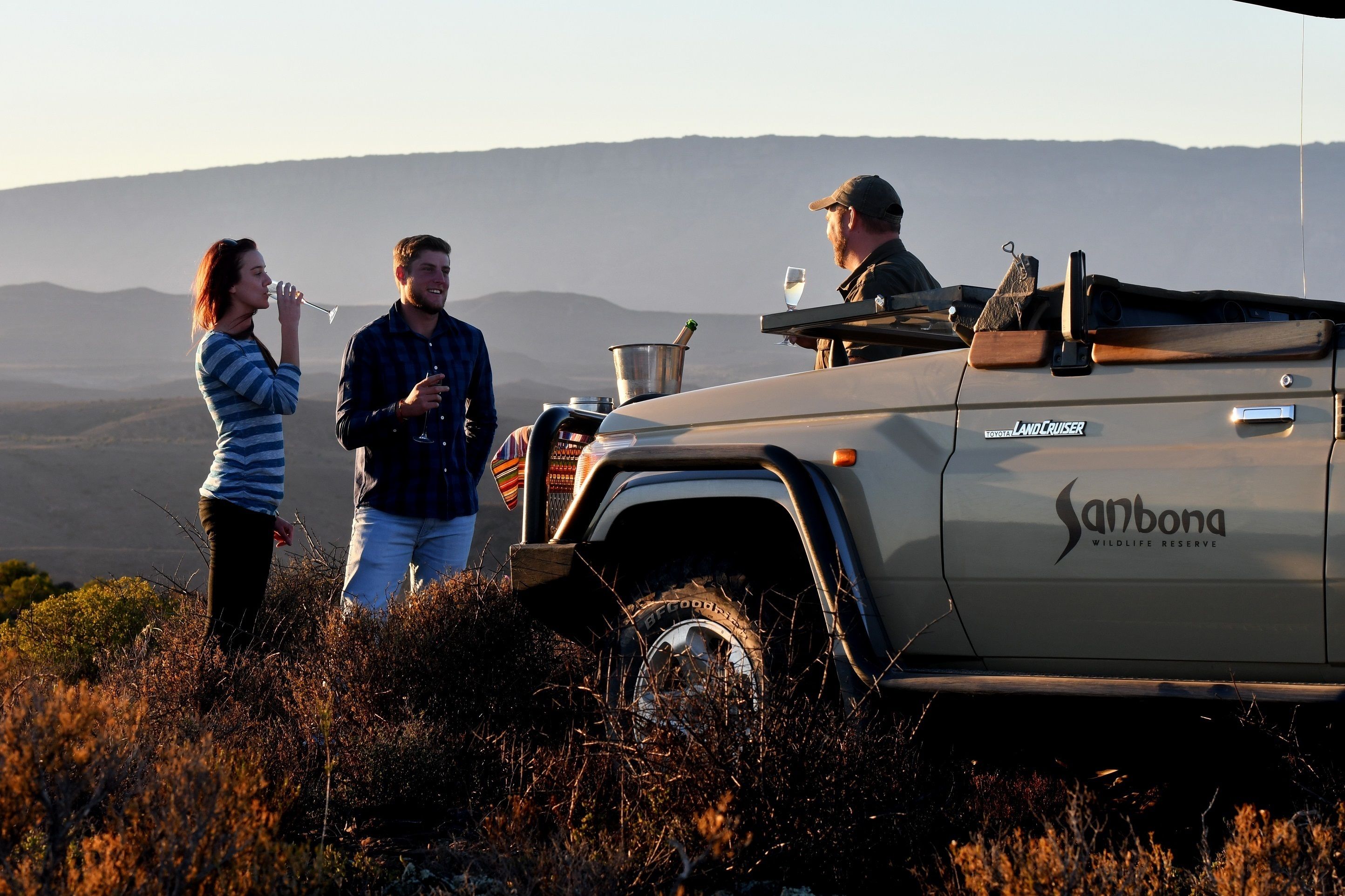 A vehicle with "Sanbona Wildlife Reserve" branding parked in a natural setting.