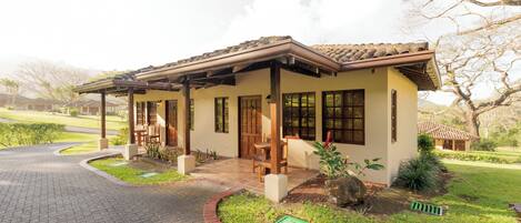 Uma casa com varanda, um pequeno jardim e um caminho de entrada calçado.