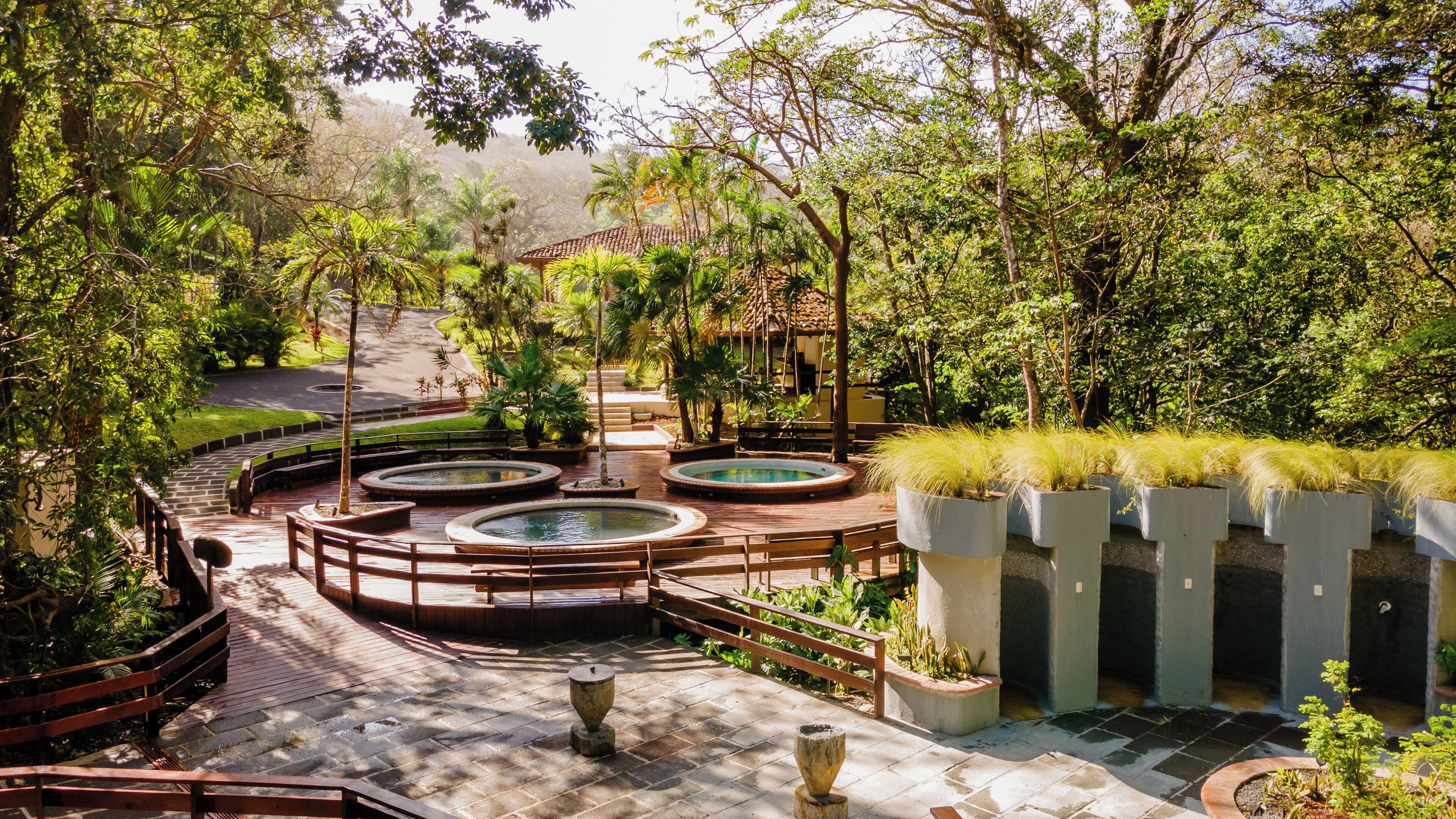 A garden with multiple circular water features, wooden walkways, and potted plants.