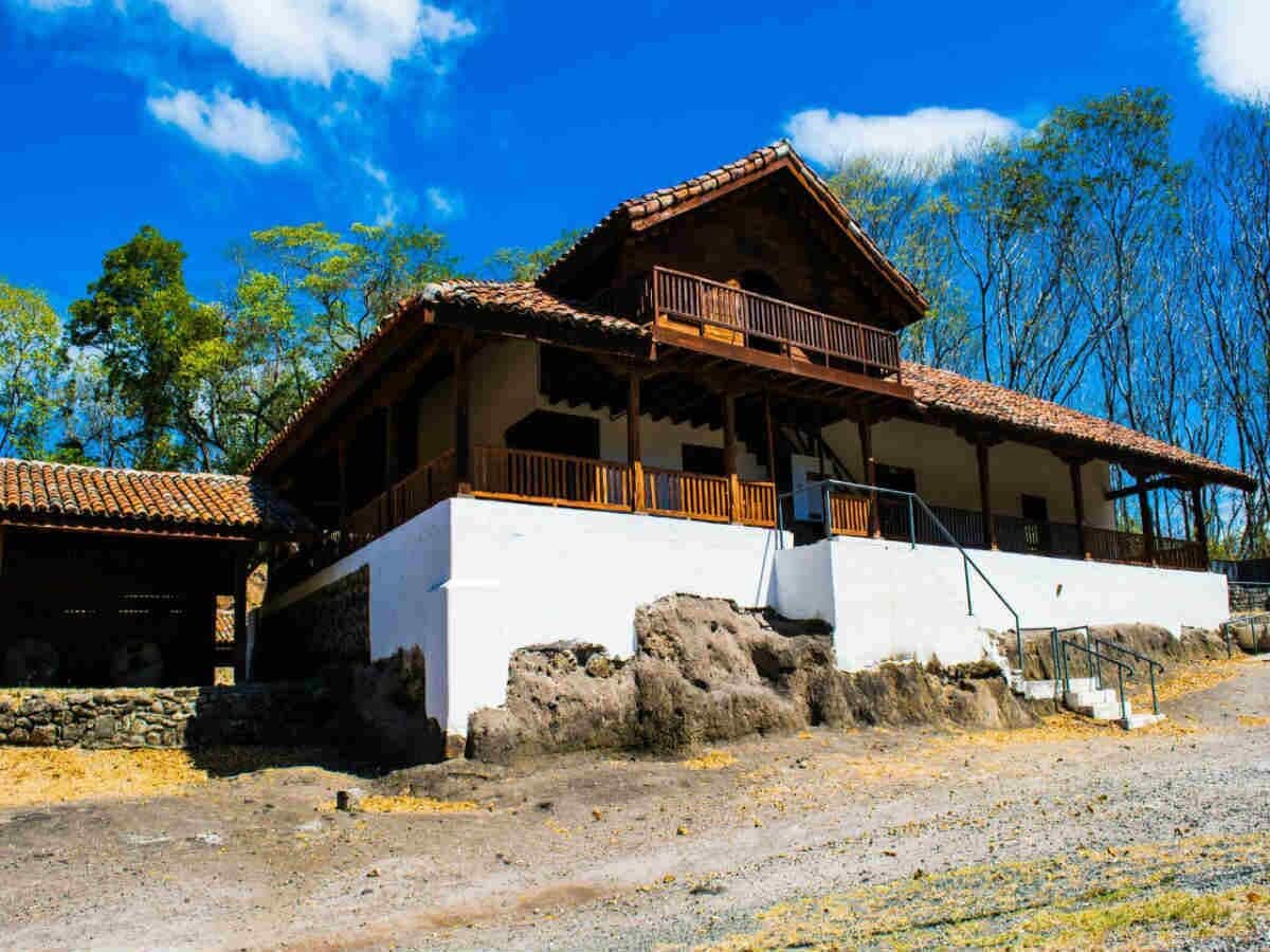 A traditional wooden building with a balcony, white walls, and a stone base.