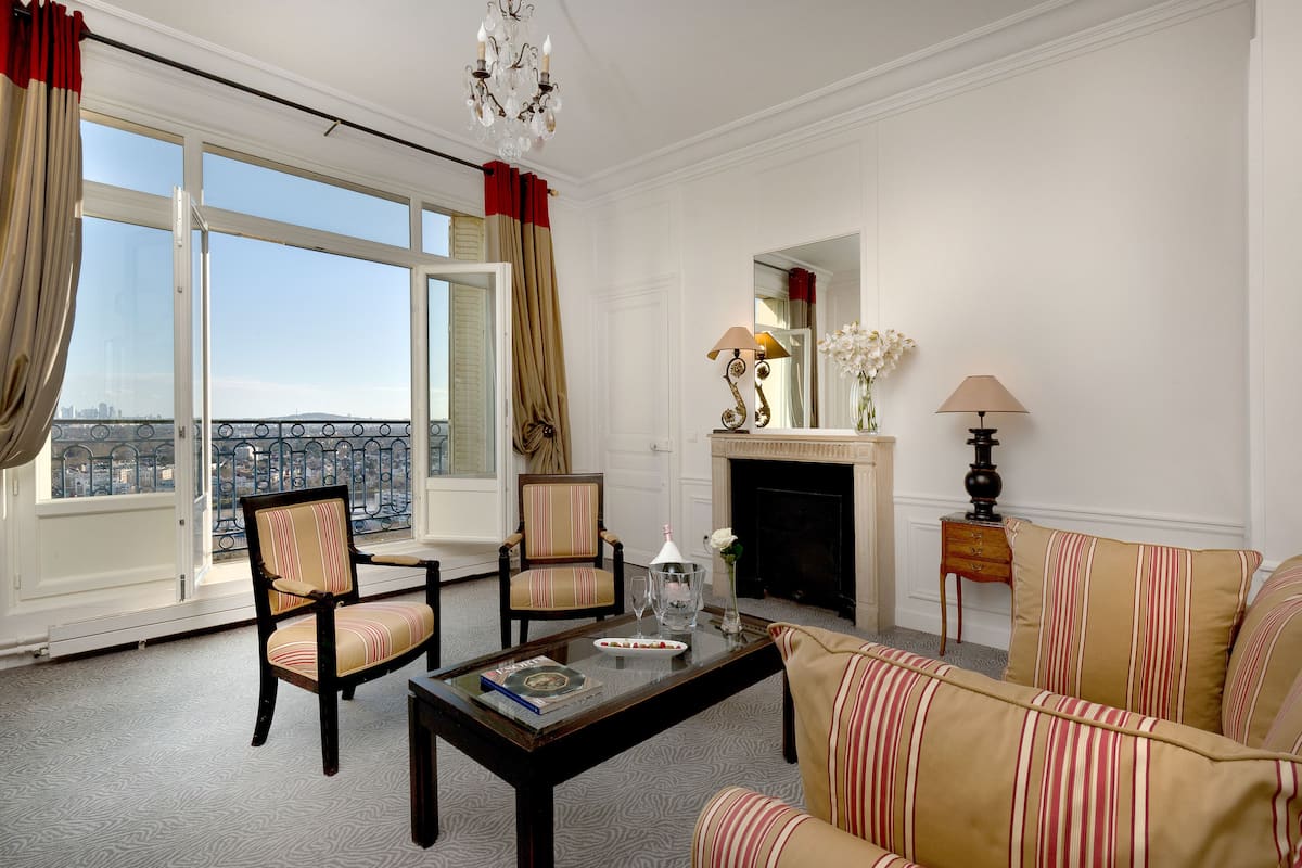A spacious room with a large window, a fireplace, and a view of the city.