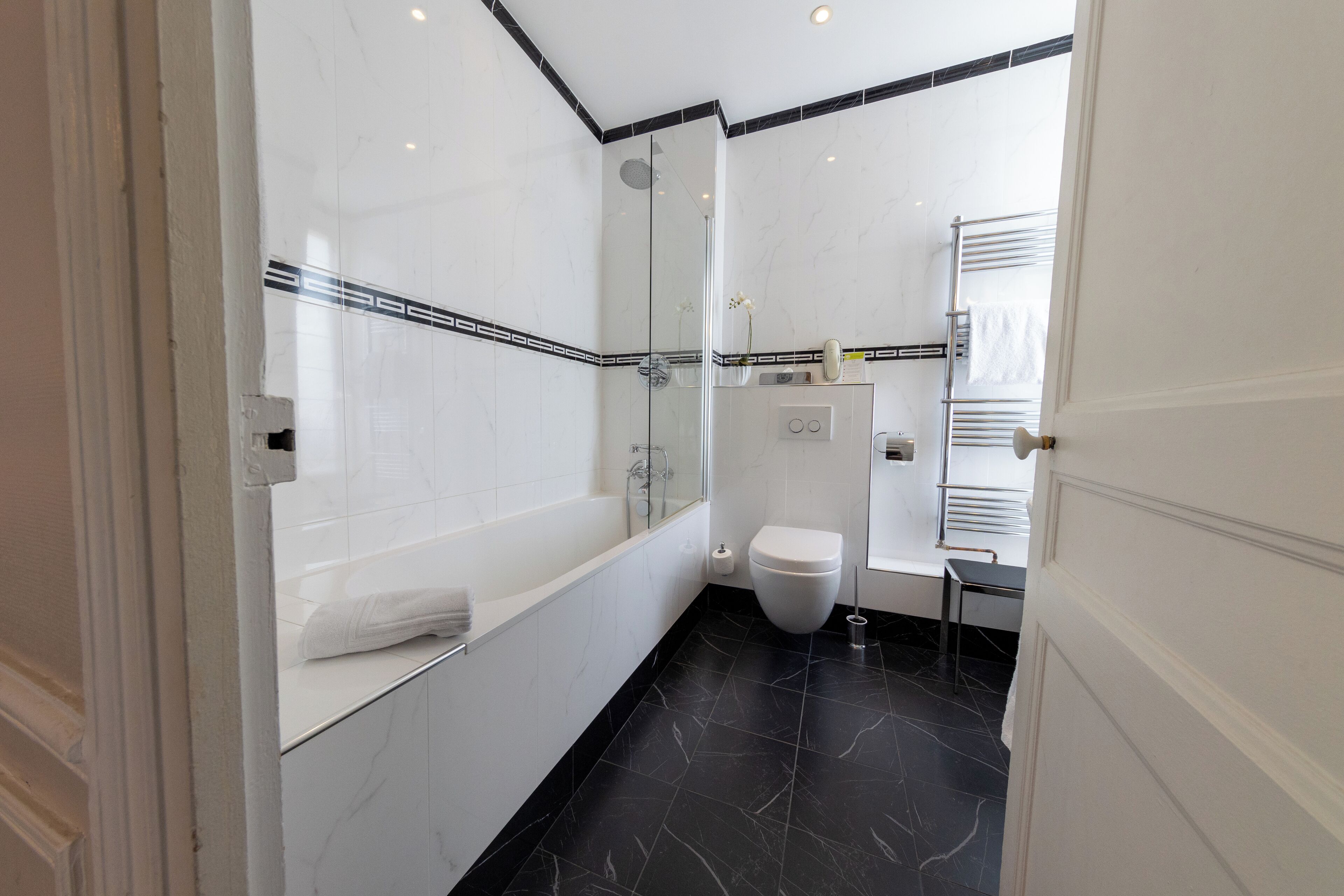 Un baño moderno con ducha de vidrio, bañera blanca y retrete.