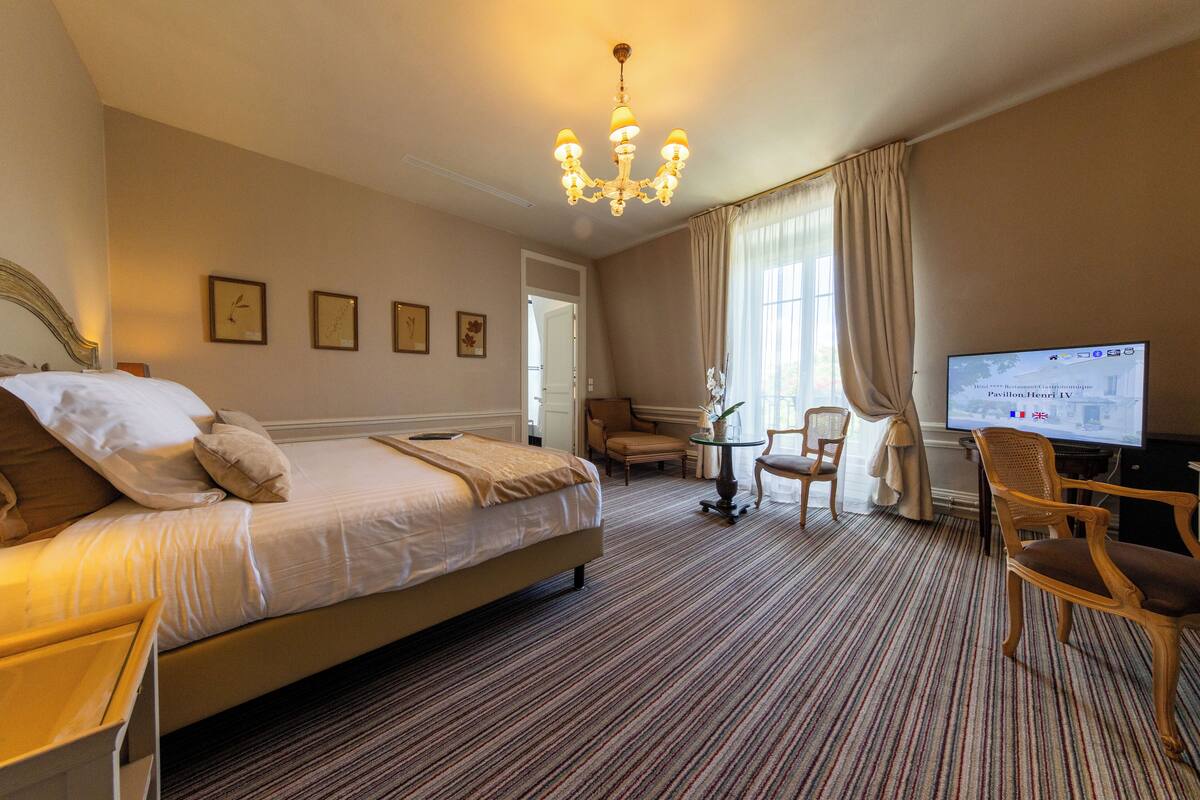 A hotel room with a large bed, a television, a small table, and two chairs.