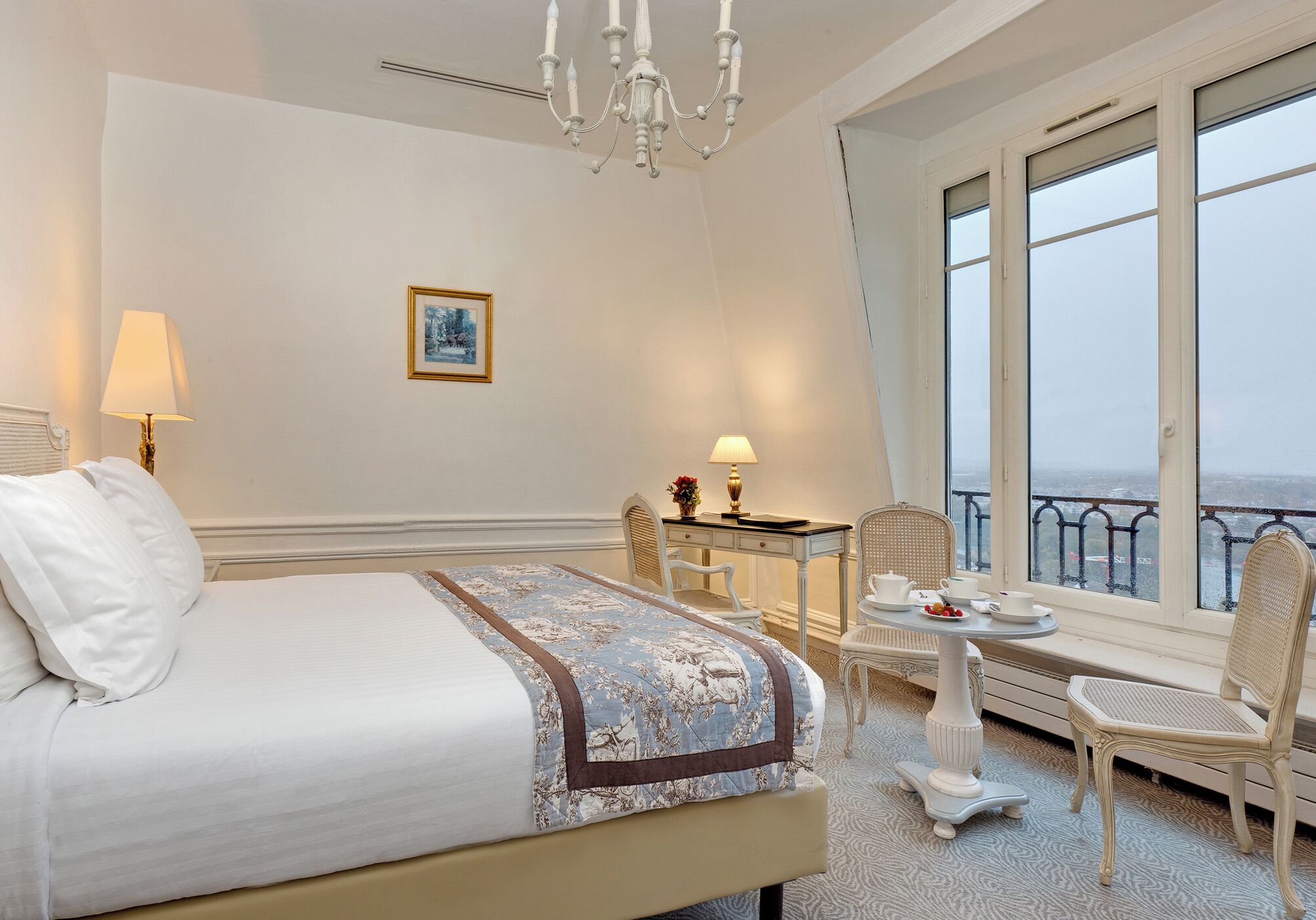 Ein Hotelzimmer mit Bett, Schreibtisch mit Stuhl, Tisch mit Stuhl und Blick ins Freie.