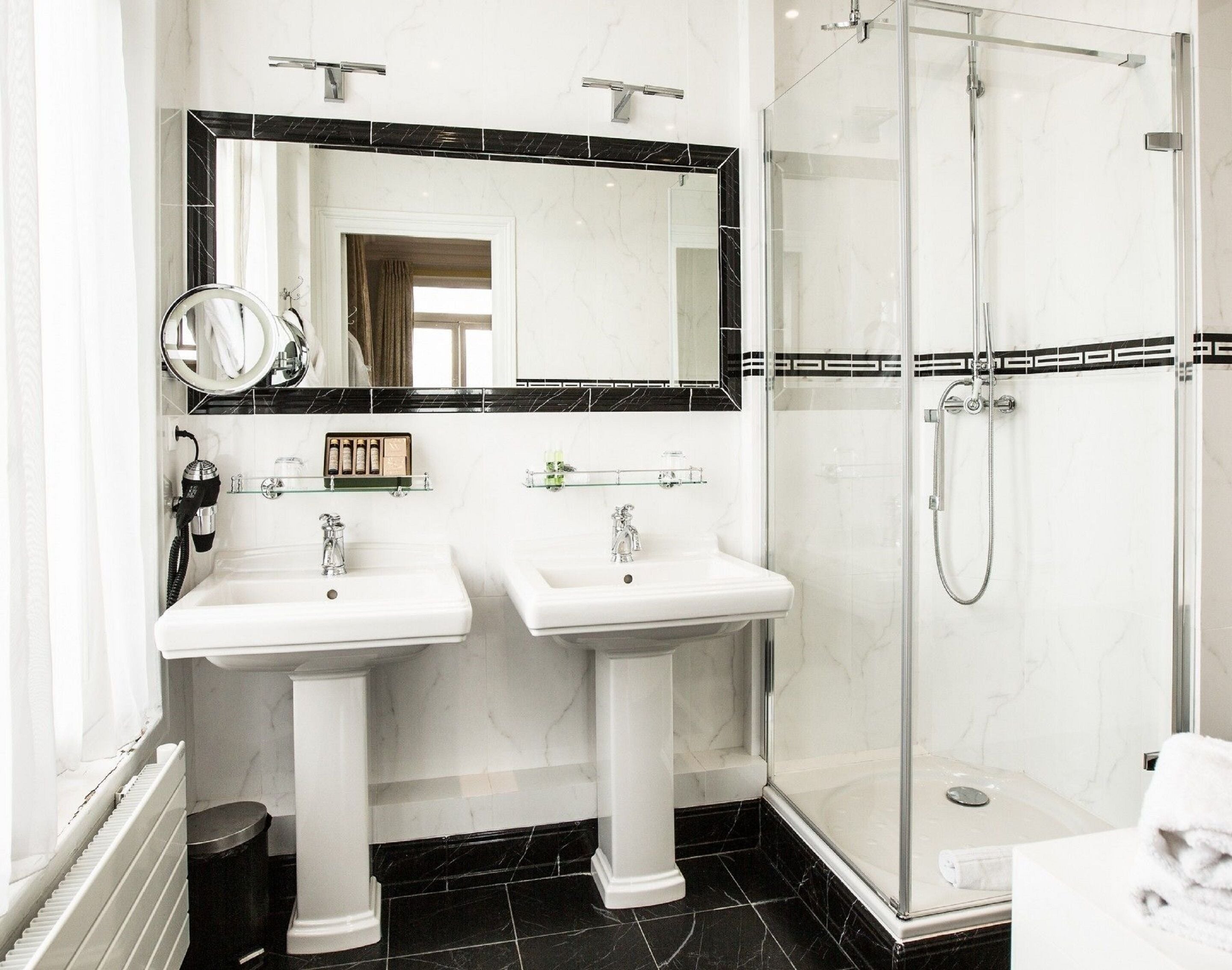 Une salle de bain avec deux lavabos, un grand miroir et une douche à parois de verre.