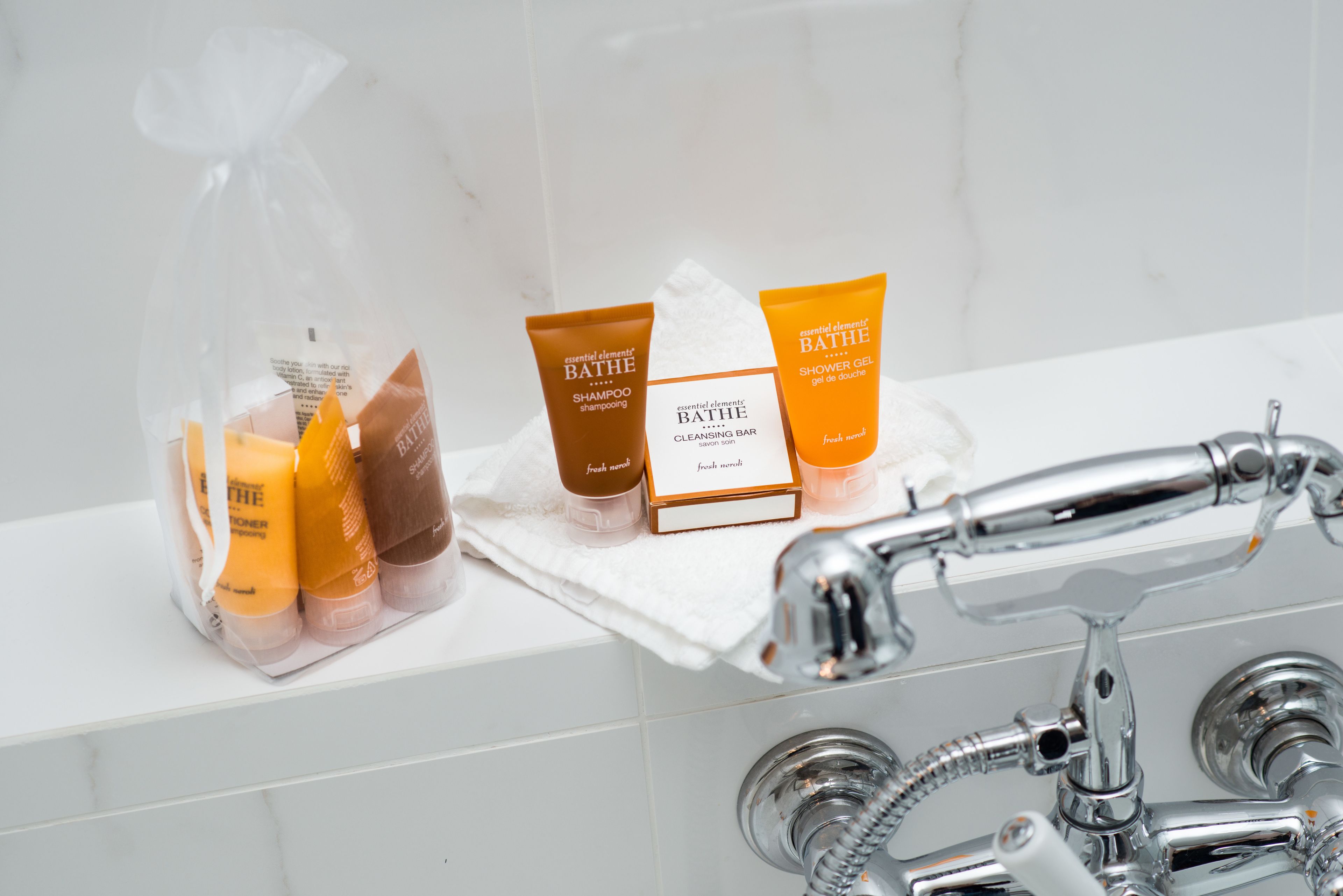 Toiletries on a bathroom shelf, including a cleansing bar and two shower gels.
